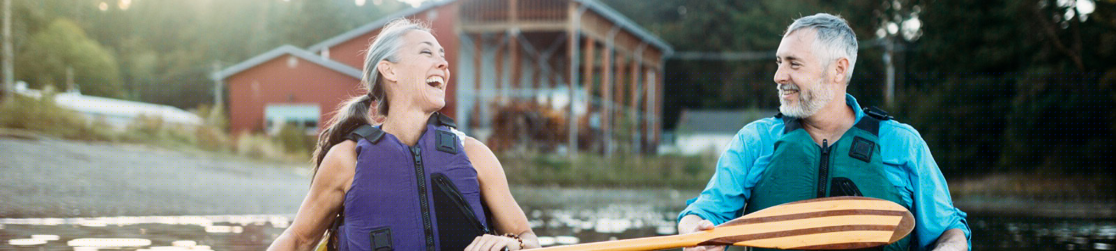 Couple smiling and paddling on a lake.