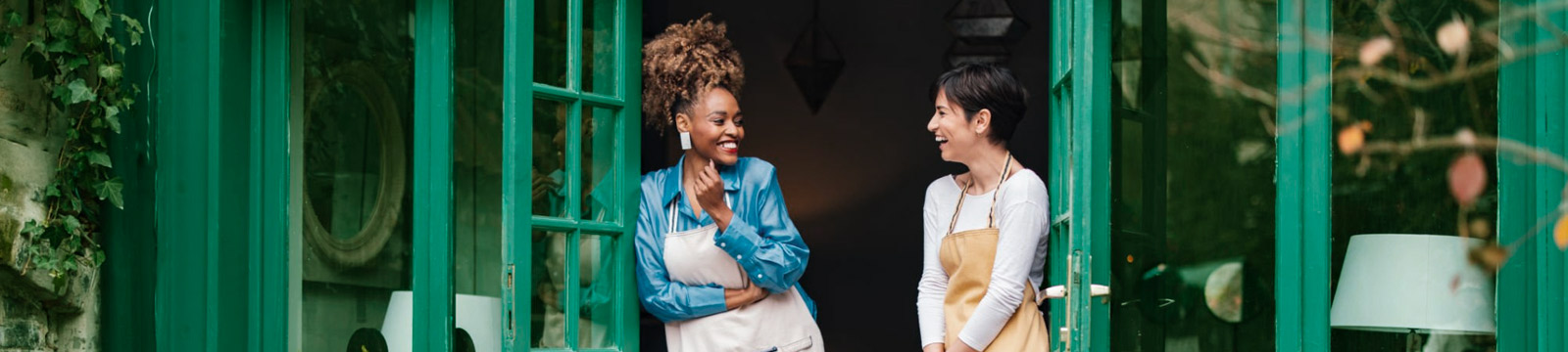 Two business partners standing in front of their shop talking.